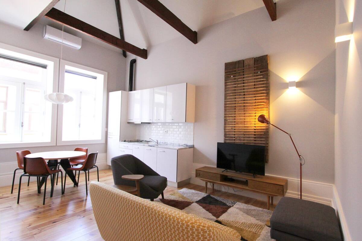 A modern living room with a sofa, chairs, a TV, and a dining area with a table and chairs.