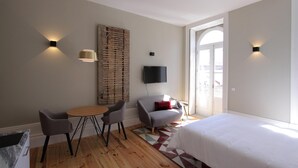 A modern hotel room with a bed, a TV, a dining area with chairs, and a large window. - Duque de Loulé (Porto)