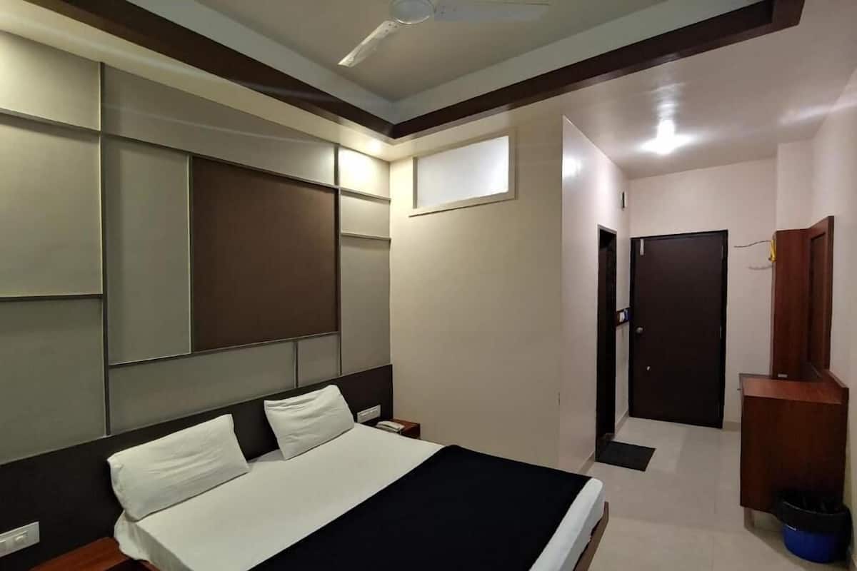 Una habitación de hotel con cama, mesitas de noche, armario y puerta.