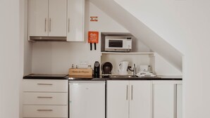 Eine kompakte Küche mit weißen Schränken, einer Mikrowelle, einer Kaffeemaschine und einem Toaster.