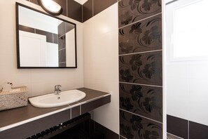A bathroom with a white sink, dark countertop, and floral-patterned tiles. - Villa in a small village on the island of Oleron (Dolus-d'Oléron)