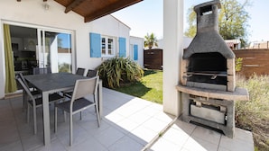 An outdoor patio with a stone barbecue grill, a dining table with chairs, and a covered area with a wooden ceiling. - High-end detached house, in a small village on the island of Oleron (Dolus d'Oleron au hamlet les Bardieres at 4 grande rue) in a charming property. (Dolus-d'Oléron)