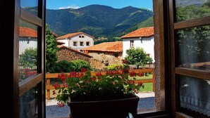 A view from a window overlooking a village with traditional buildings and mountains in the background.