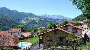 A stone building with a swimming pool, surrounded by a mountainous landscape.