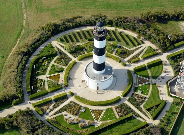 A lighthouse with a circular garden layout, a central water feature, and a surrounding road. - Paradiles Villa Le Goéland (Dolus-d'Oléron)