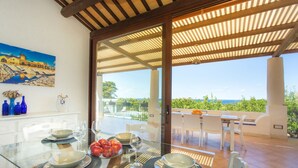A dining area with a glass table, white chairs, and a view of the sea. - Independent villa between Trapani and San Vito Lo Capo, with swimming pool and sea view (Valderice)