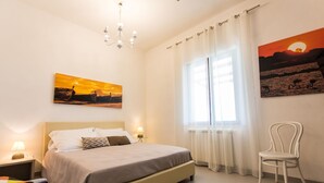 A bedroom with a bed, two bedside tables with lamps, a chair, and two paintings on the walls. - Independent villa between Trapani and San Vito Lo Capo, with swimming pool and sea view (Valderice)