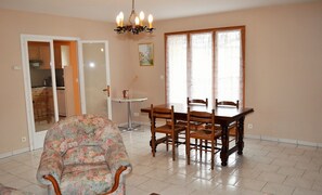 A dining area with a wooden table and chairs, a floral armchair, and a chandelier.