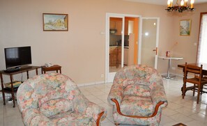 A living room with two floral armchairs, a television, and a dining area with a table and chairs. - Peaceful farmhouse between rivers and vineyards, pets allowed (Saint-Laurent-de-Lin)