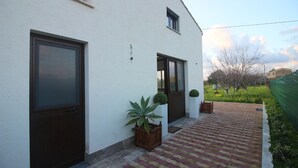 Et moderne hus med en anlagt terrasse, et stort vindue og en dør.