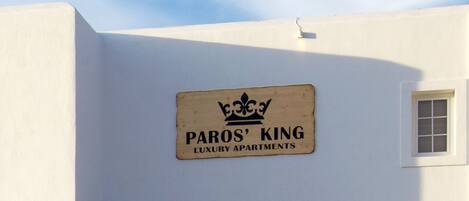 Une enseigne indiquant « Paros, appartements de luxe » sur un immeuble blanc.