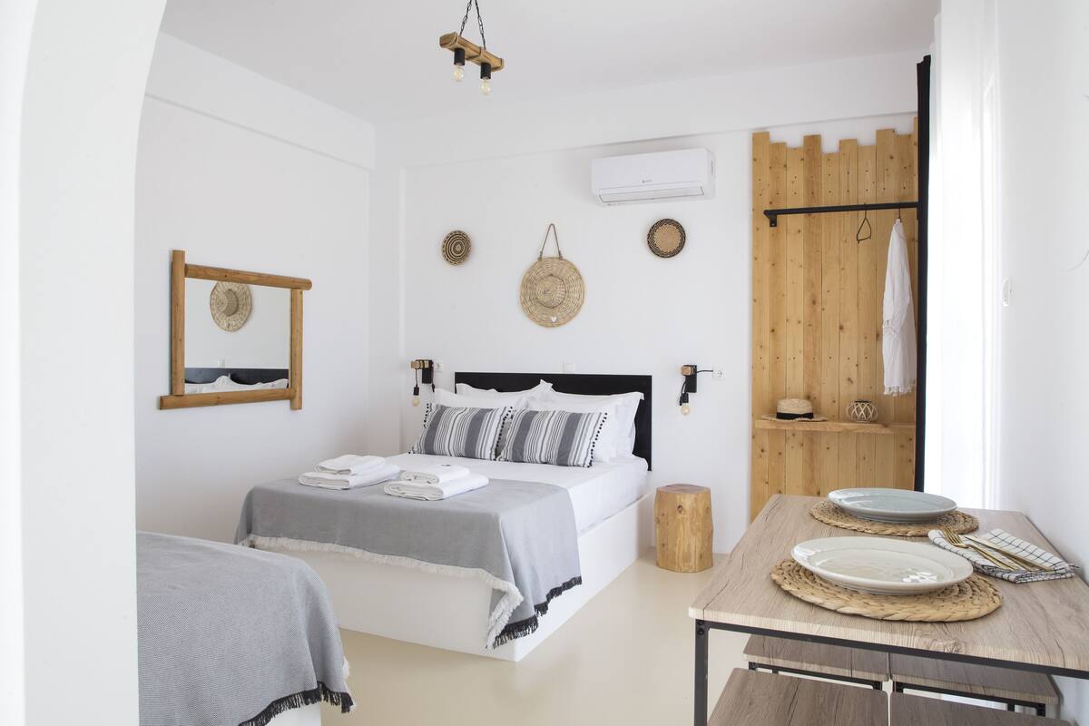 Ein Schlafzimmer mit einem Bett, Nachttischen, einem Holz-Kopfteil, einem Spiegel, Wanddekoration und einer Klimaanlage.