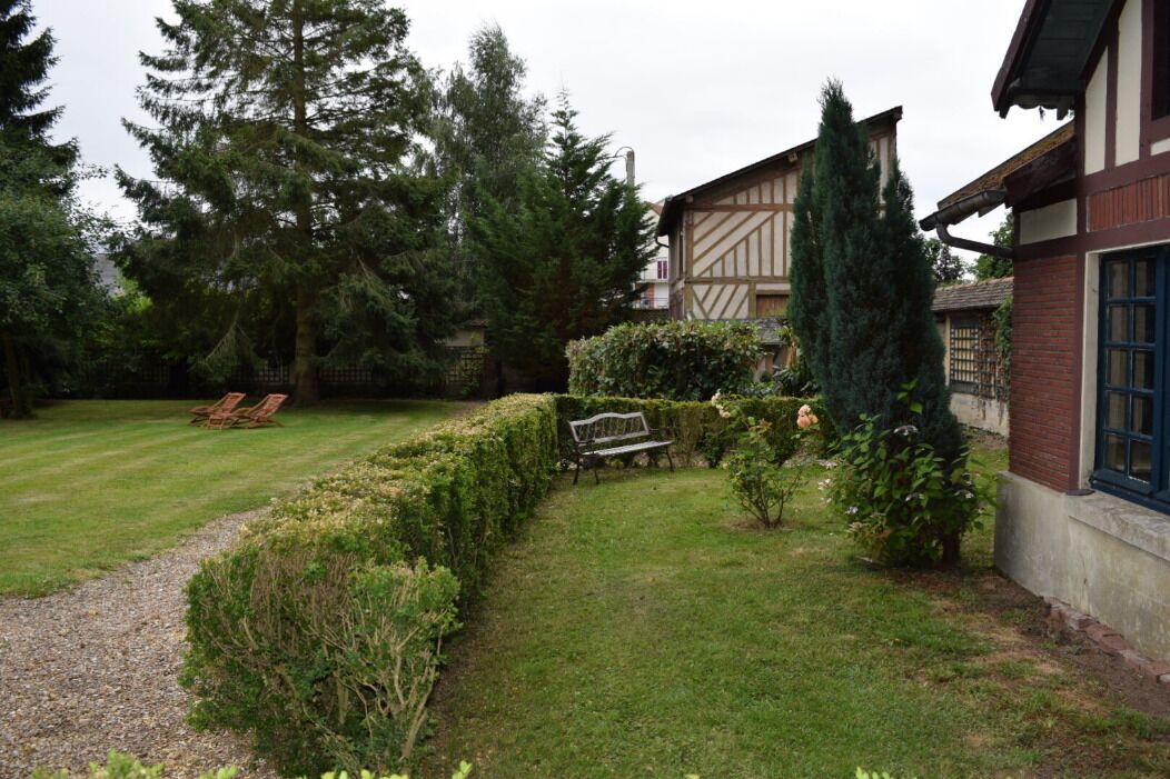A garden with a bench, a path, and a building with a window.
