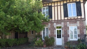 A traditional half-timbered house with a brick facade, a white door, and a small garden with potted plants. - Character house near Honfleur (Beuzeville)