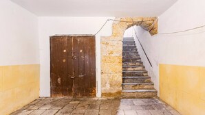 A narrow hallway with a wooden door and a stone staircase. - Apartment in the heart of the Ballarò market (Palermo)