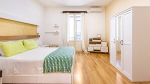 A bedroom with a bed, bedside tables, a wardrobe, and a window with curtains. - Apartment in the heart of the Ballarò market (Palermo)