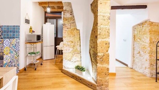 A kitchen with a white refrigerator, a microwave, and a tiled backsplash. - Apartment in the heart of the Ballarò market (Palermo)