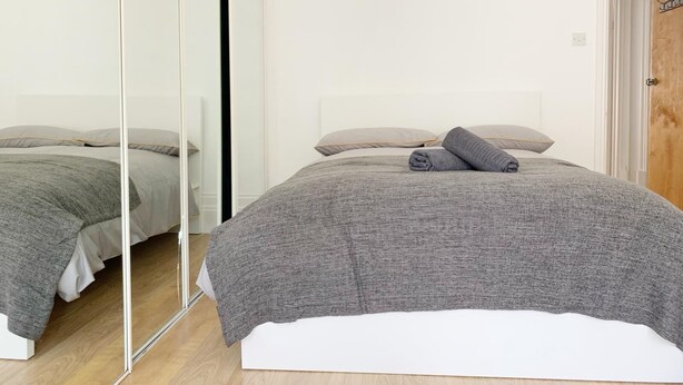 Une chambre à coucher avec un lit, un miroir et une porte en bois.
