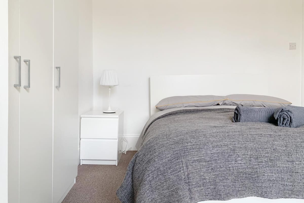 A bedroom with a bed, a nightstand, a lamp, and a wardrobe.