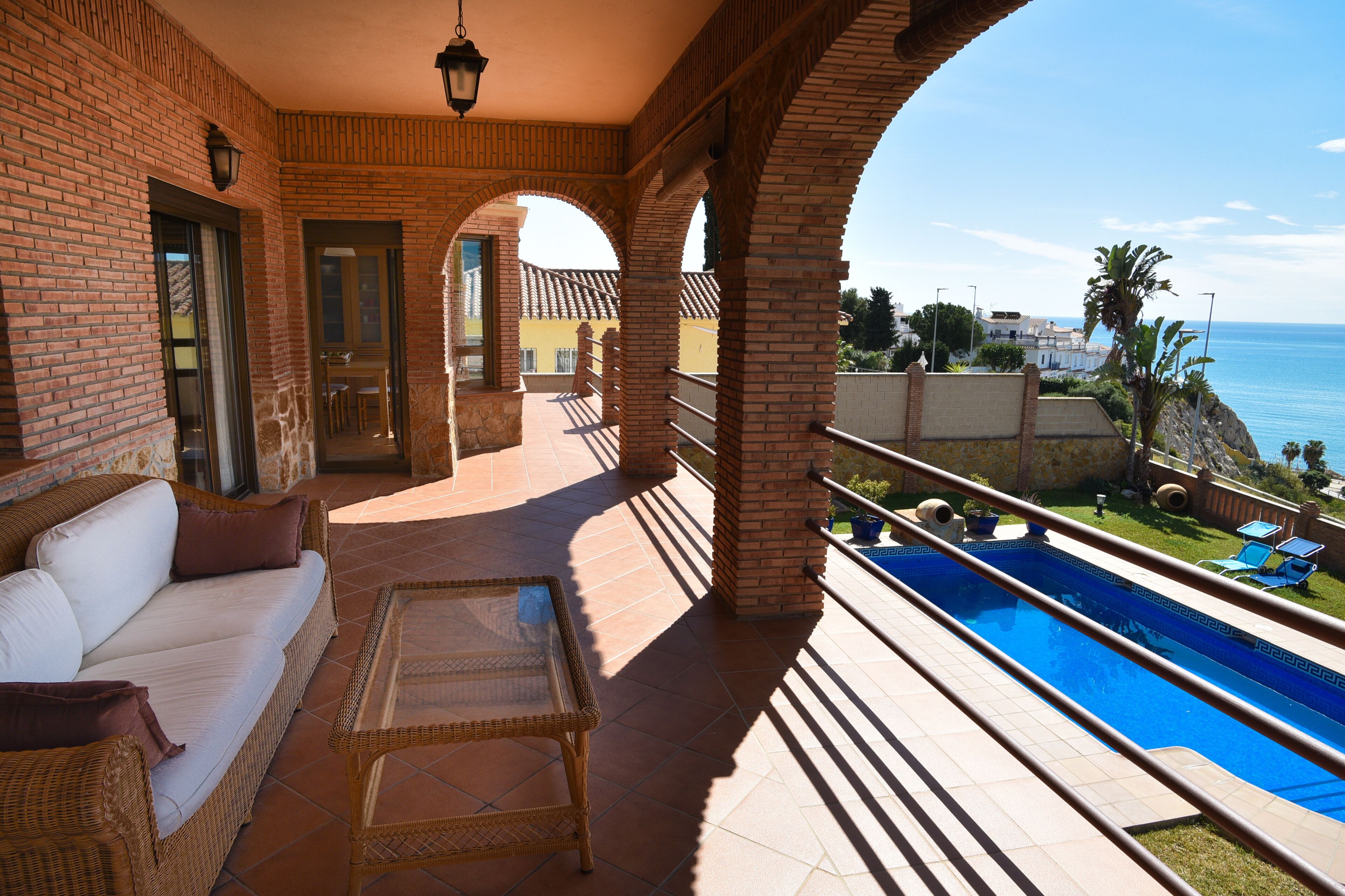 A terrace with a pool, a sofa, and a table.