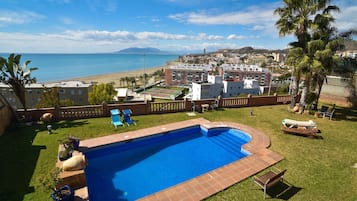 Una piscina al aire libre, sombrillas, sillones reclinables de piscina