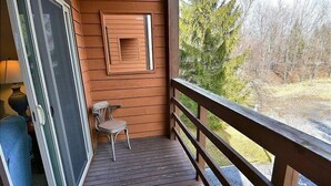 Une terrasse en bois avec une porte vitrée, une chaise et une petite table.