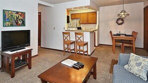Un salon avec un téléviseur, une table basse et un canapé. Il y a également un coin repas avec une table et des chaises.