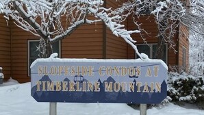 Une enseigne indiquant « Slopeside Condos at Timberline Mountain », avec un paysage enneigé en arrière-plan.
