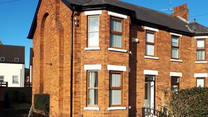 A two-story brick house with a front door, windows, and a small garden area. - Delightful Victorian House (Belfast)