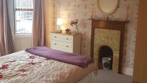 A bedroom with a bed, dresser, mirror, and fireplace. - Delightful Victorian House (Belfast)