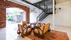 A room with a brick archway, a staircase, and a seating area with wooden chairs and a round table. - Super OYO Collection O 2383 Andongkoe 64 Salatiga (Salatiga)