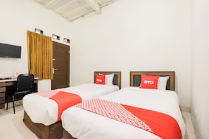 Une chambre d’hôtel avec deux lits, un bureau, une chaise et un téléviseur.