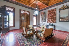A traditional room with a wooden ceiling, a patterned floor, a round table with chairs, a bicycle, and a mirror. - Super OYO Collection O 2383 Andongkoe 64 Salatiga (Salatiga)