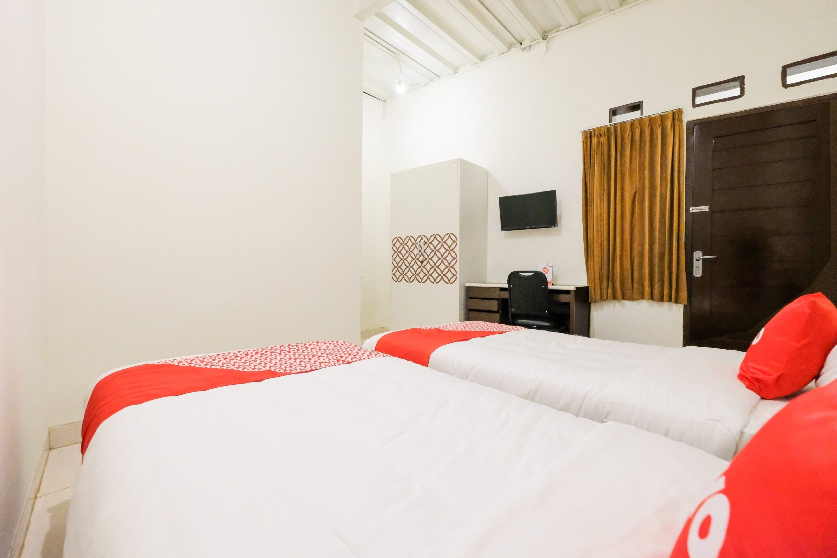 A hotel room with two beds, a TV, a desk, and a wardrobe.