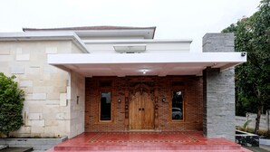 A modern house with a large wooden door, a covered entrance, and a stone wall. - Super OYO Collection O 2383 Andongkoe 64 Salatiga (Salatiga)