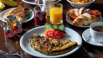 A breakfast setting with toast, a plate of vegetables, a croissant, a glass of orange juice, and a cup of coffee.