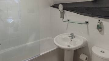 Un baño con cabina de ducha de vidrio, un lavamanos blanco, un espejo y un inodoro.