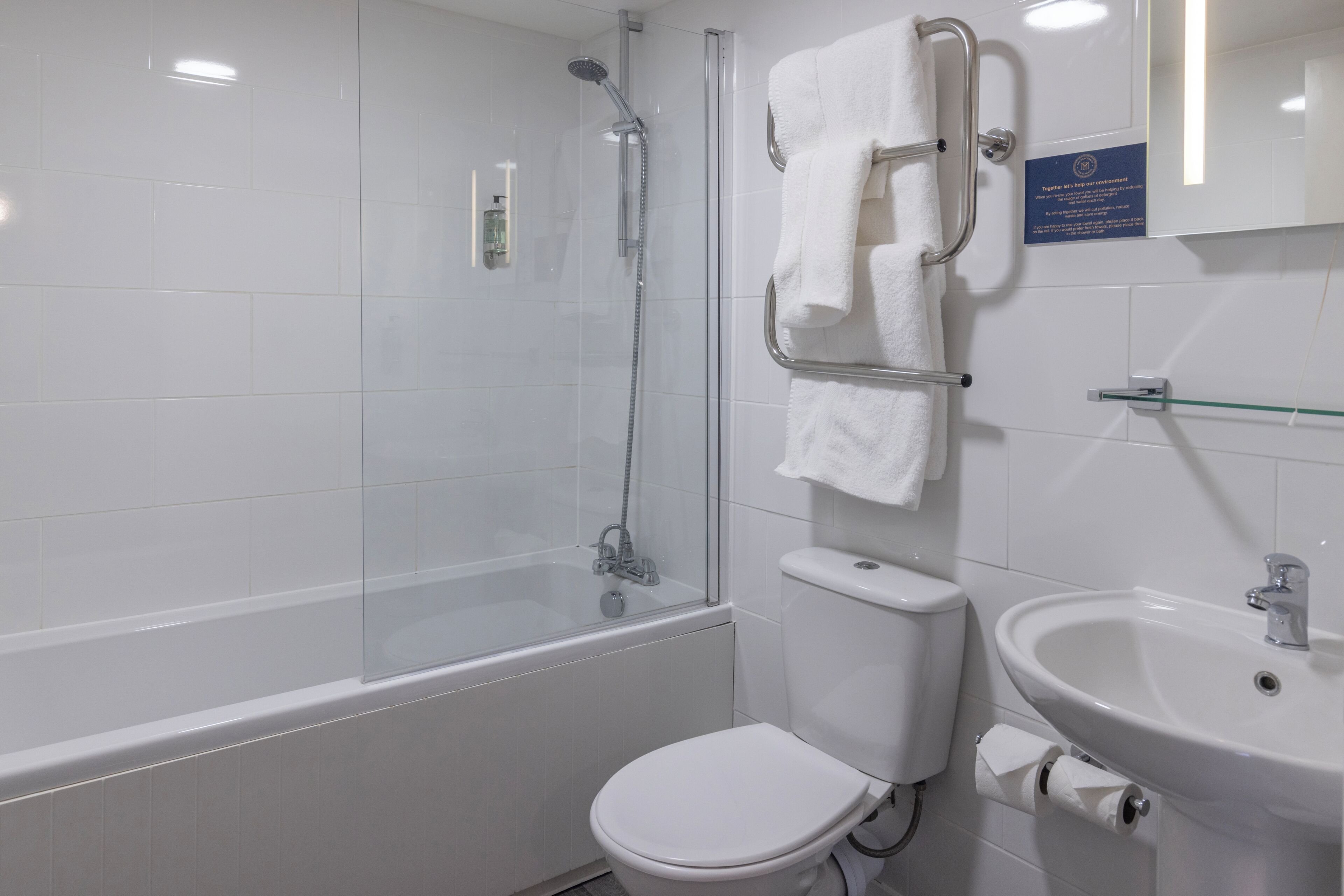Une salle de bain avec une douche à parois de verre, des toilettes blanches et un lavabo avec un miroir au-dessus.