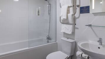 Un baño con ducha envuelta en vidrio, inodoro blanco y lavamanos con espejo superior.