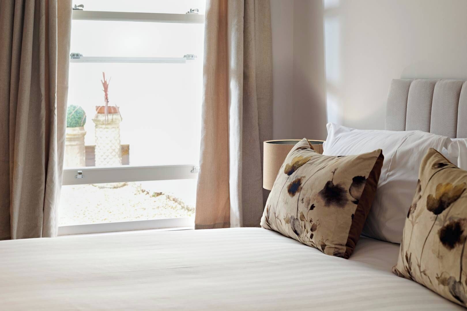 Habitación de hotel con una cama, vista a un edificio y una ventana con cortinas.