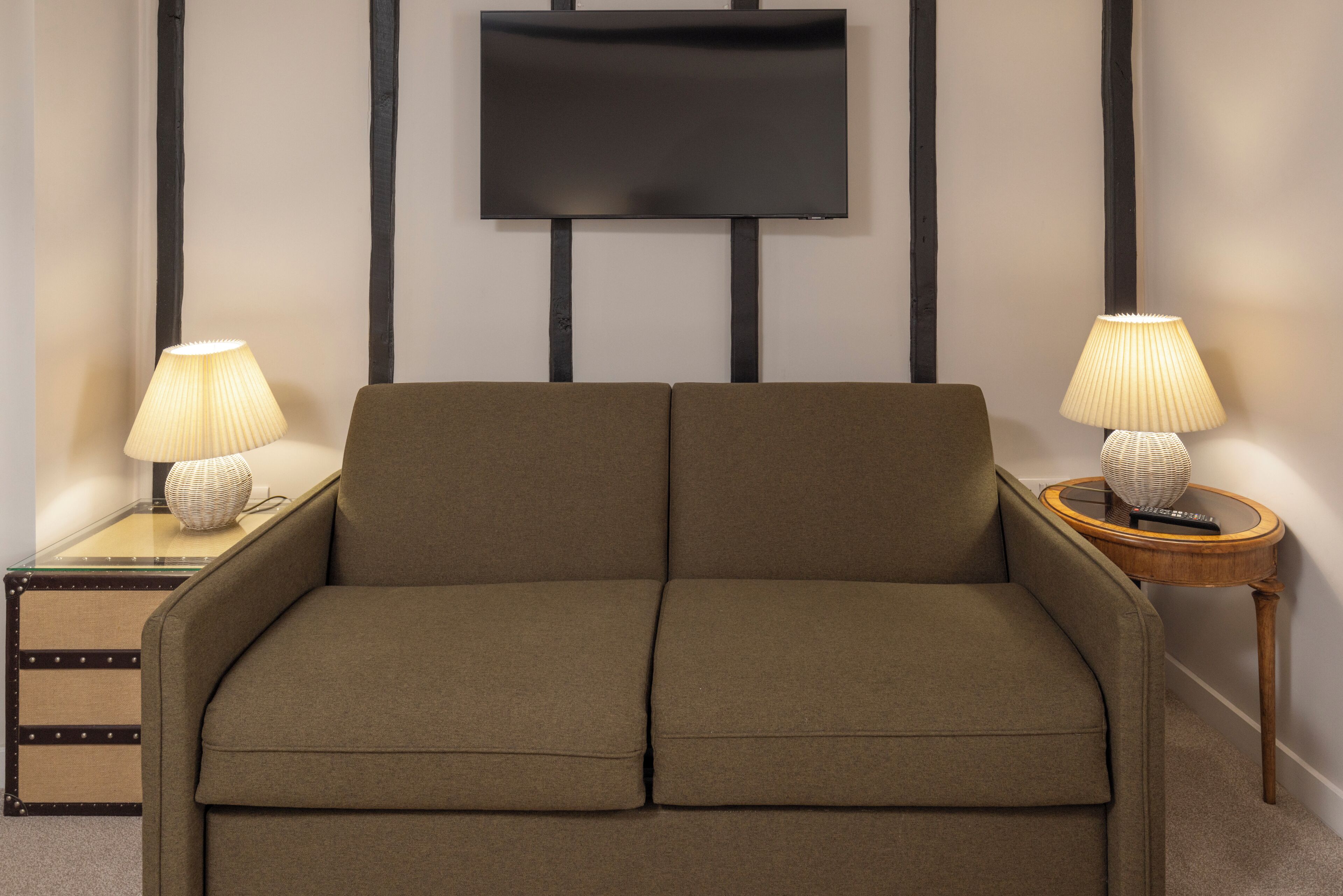 Una habitación con sofá, dos lámparas, televisor y una mesita auxiliar.