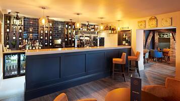 A bar area with a dark blue counter, multiple hanging light fixtures, and a wine list stand.