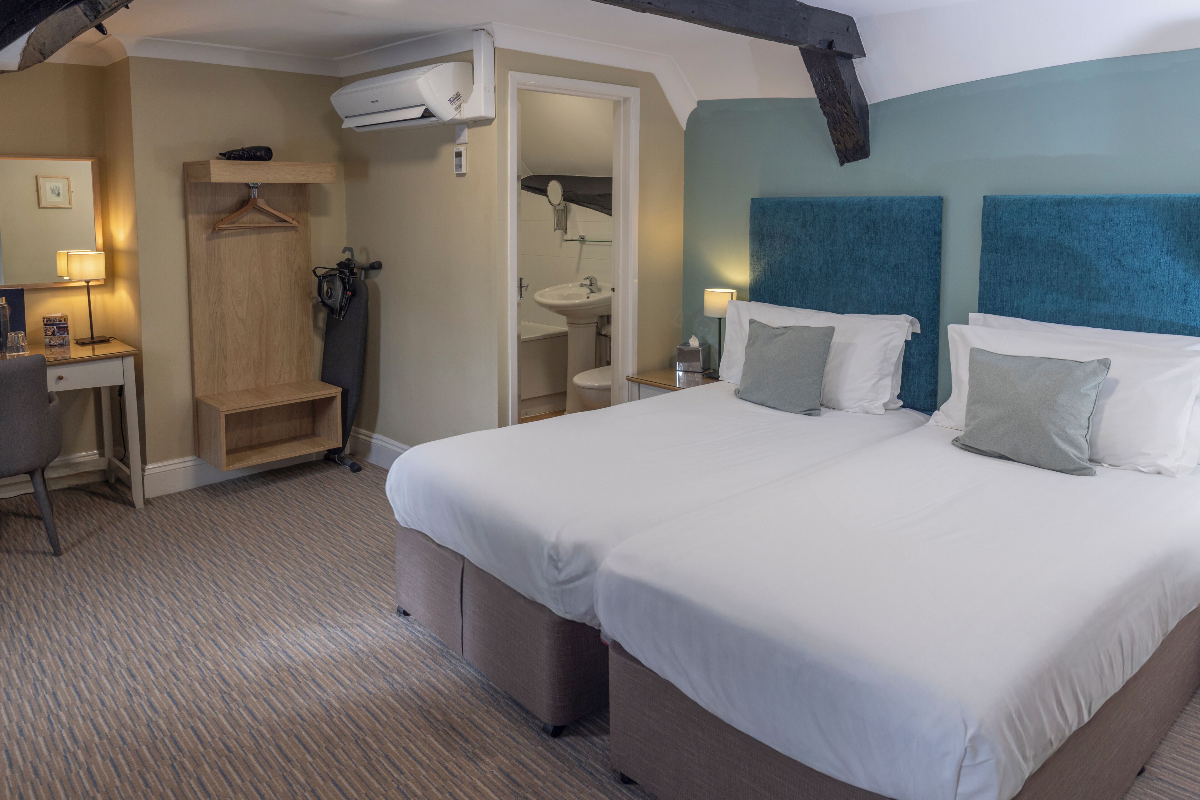 A hotel room with a large bed, a desk, a chair, a wardrobe, and a bathroom.
