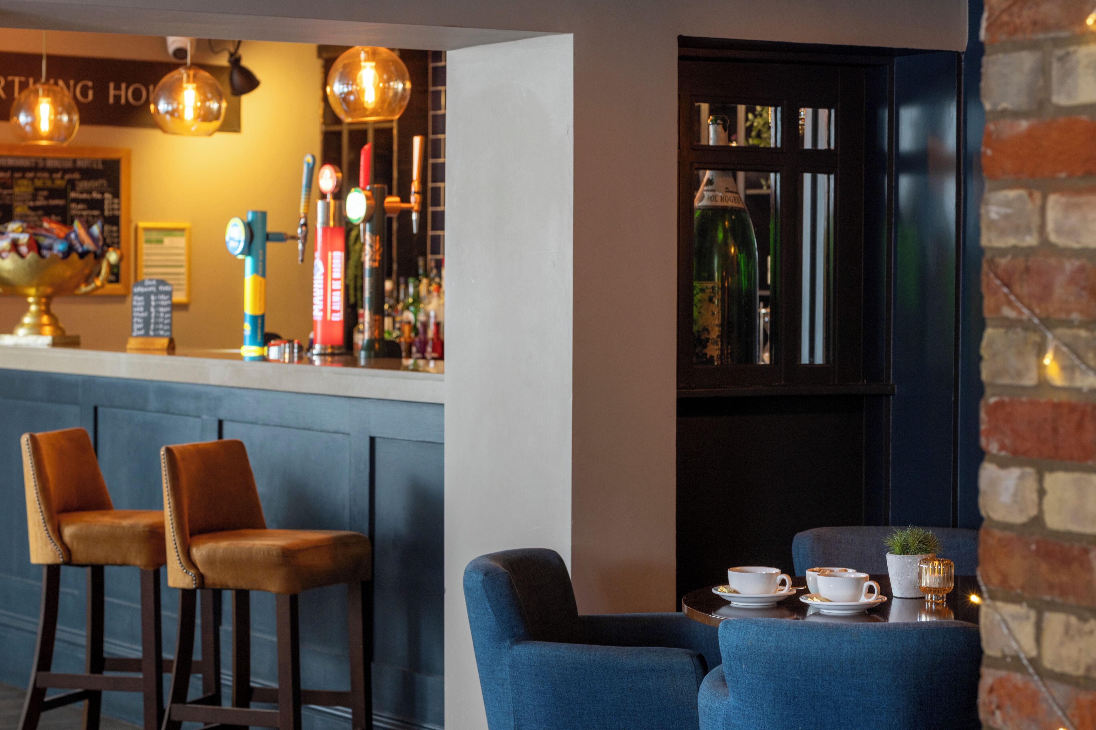 A bar area with stools, a counter with bottles, and a seating area with a table and chairs.