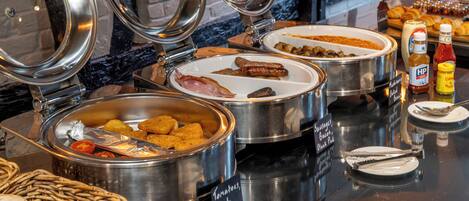 Un buffet proposant une variété de plats, notamment des saucisses, du boudin noir et des haricots cuits.