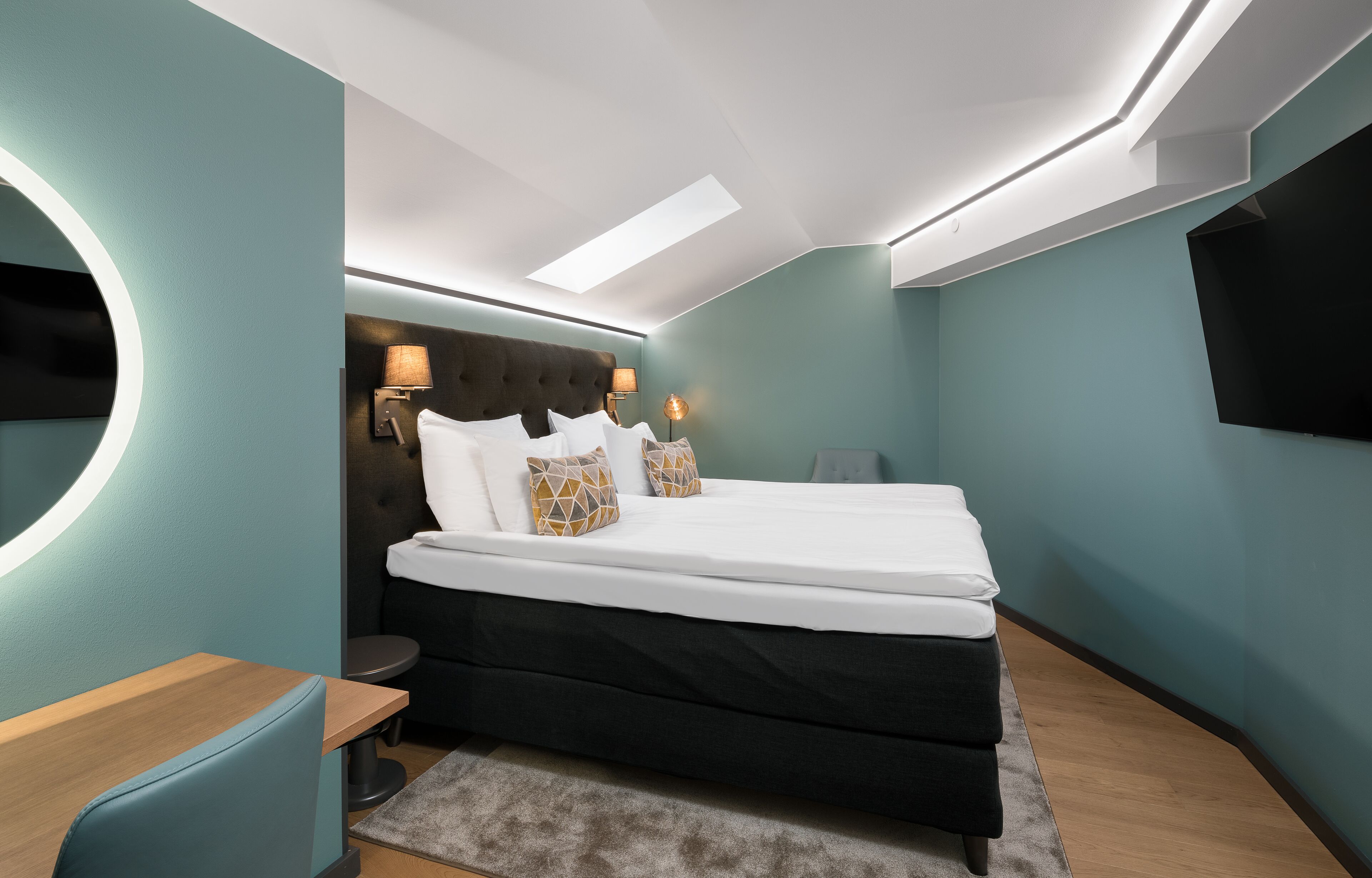 Un dormitorio moderno con cama, mesitas de noche, escritorio y televisor.