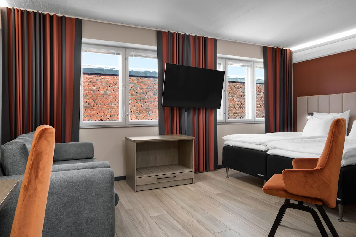 A hotel room with a bed, a TV, a sofa, and a desk.