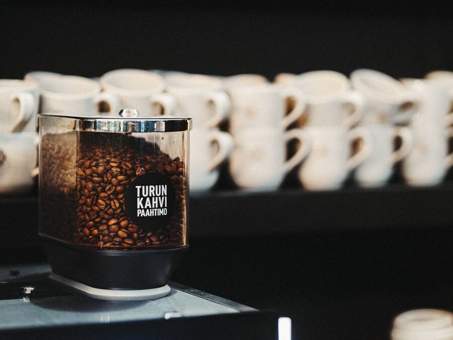A coffee grinder with visible coffee beans and a label reading "Turun Kahvi Pahtimo".