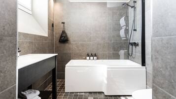 Un baño moderno con bañera, ducha e inodoro. Hay un perchero con toallas y un bolso colgado en la pared.