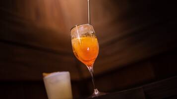 A glass of orange-colored drink with a straw, placed on a wooden surface.